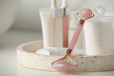 Photo of Natural face roller and tray with cosmetic products on white table, closeup