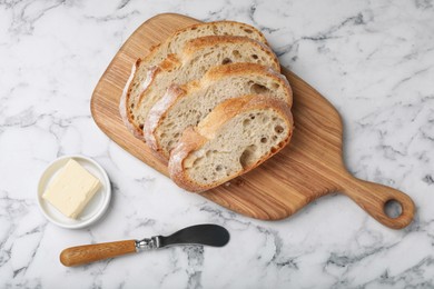 Photo of Freshly baked sodawater bread and butter on white marble table, flat lay