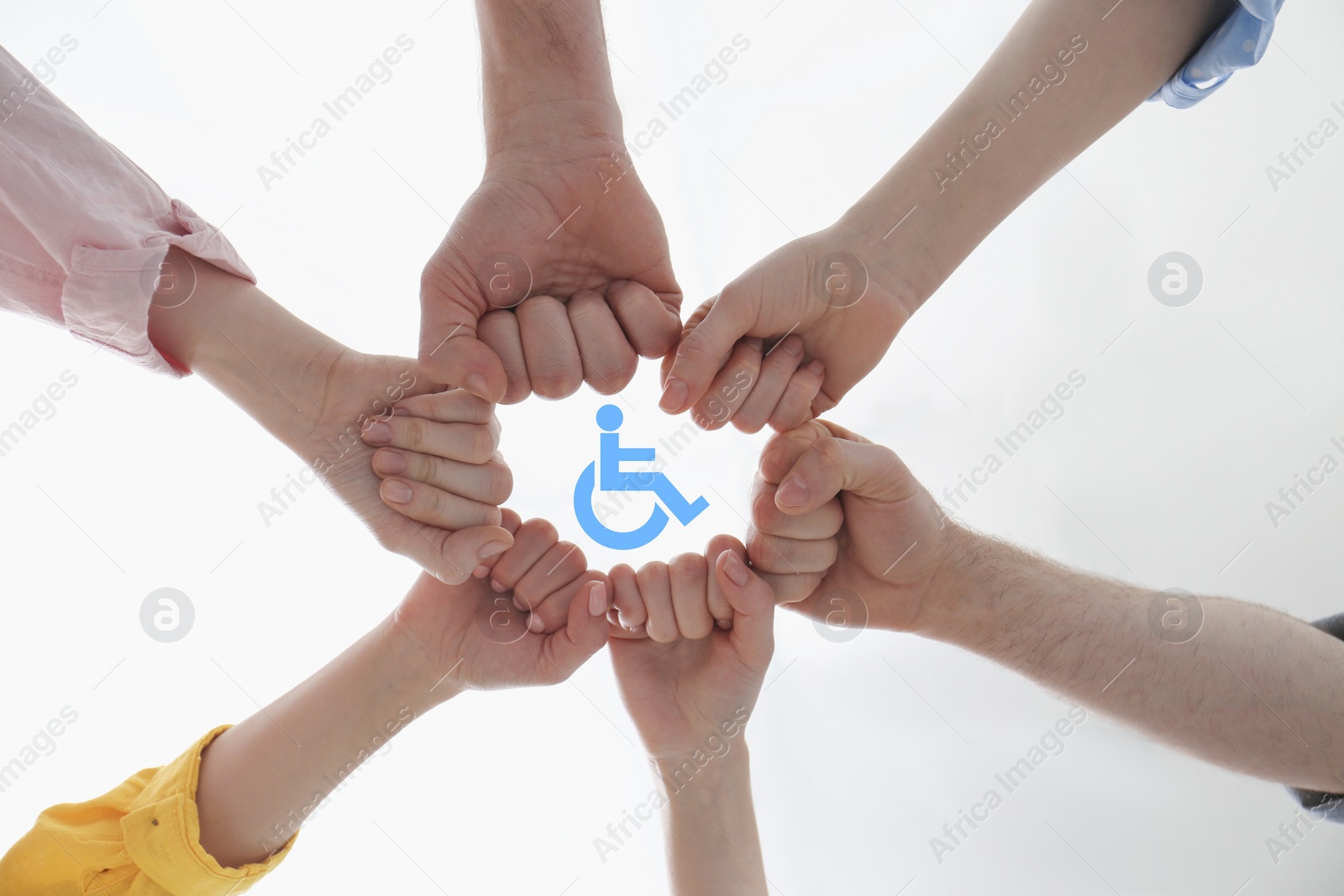 Image of Inclusion concept. People holding fists together around international symbol of access together, bottom view