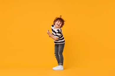 Happy little boy dancing on yellow background