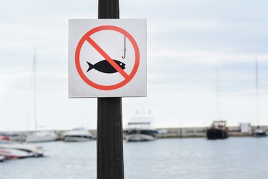 Post with No fishing sign near sea. Space for text