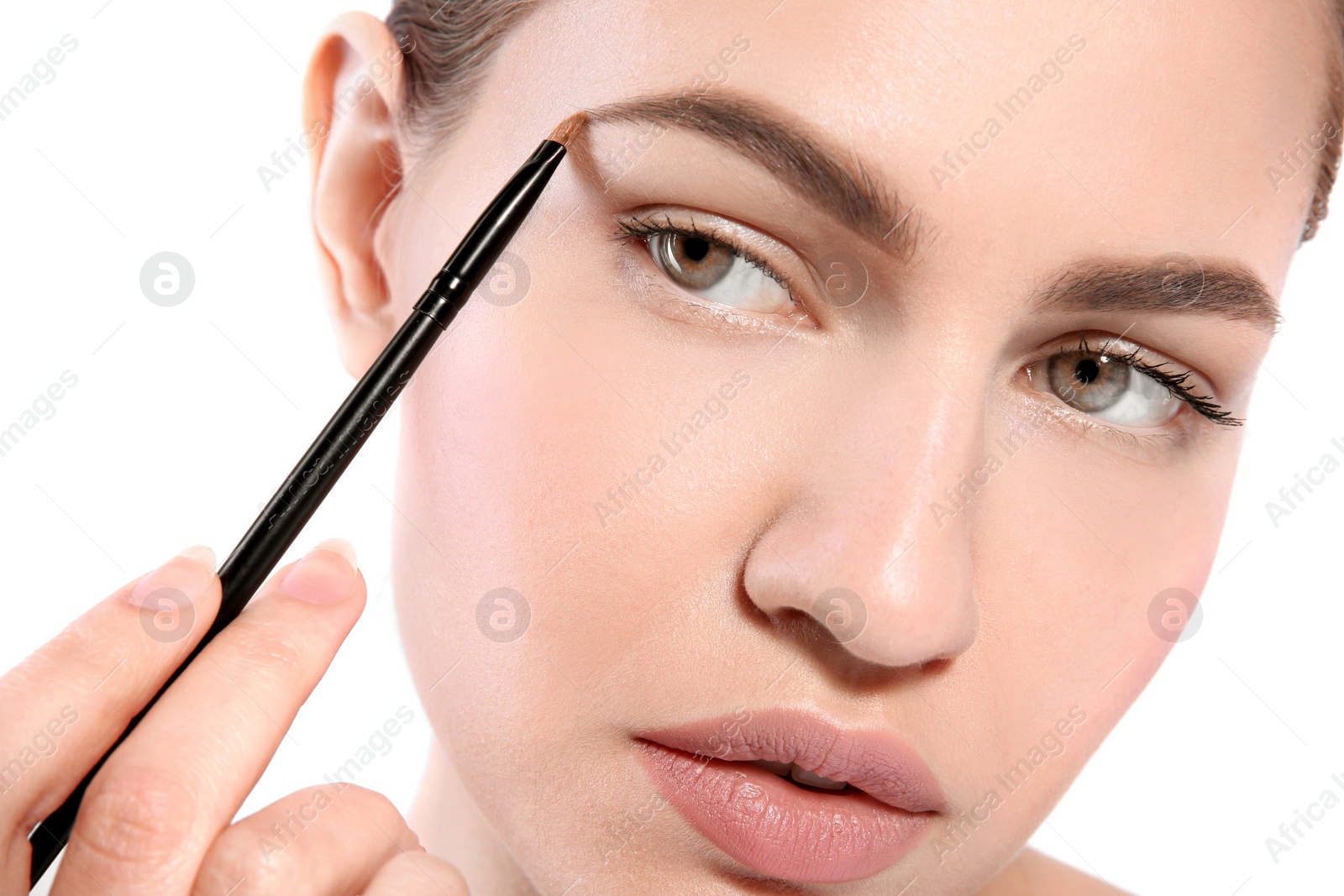 Photo of Beautiful woman with perfect eyebrows applying makeup on light background