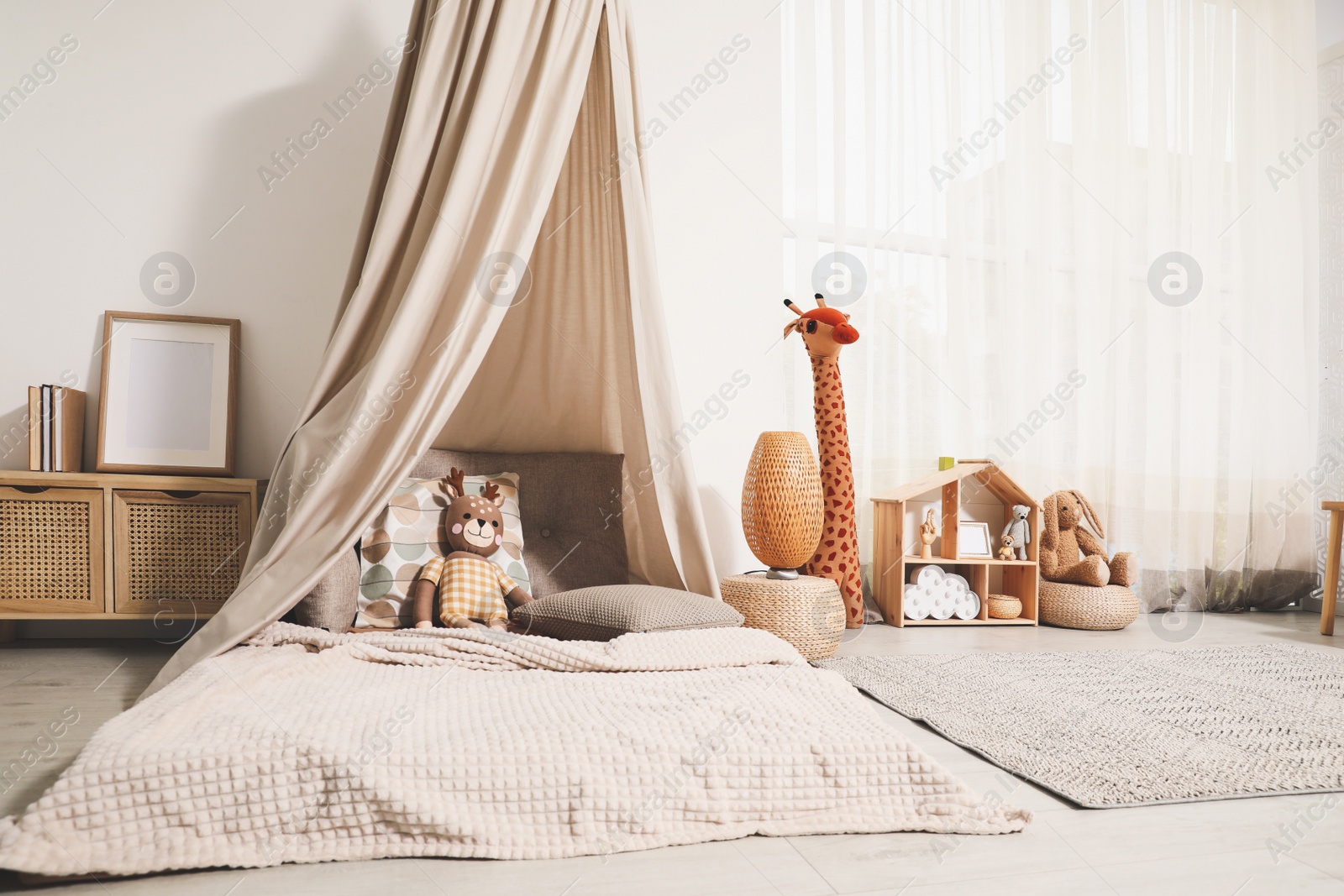 Photo of Cozy kids room with play tent, toys and comfortable floor bed. Montessori interior