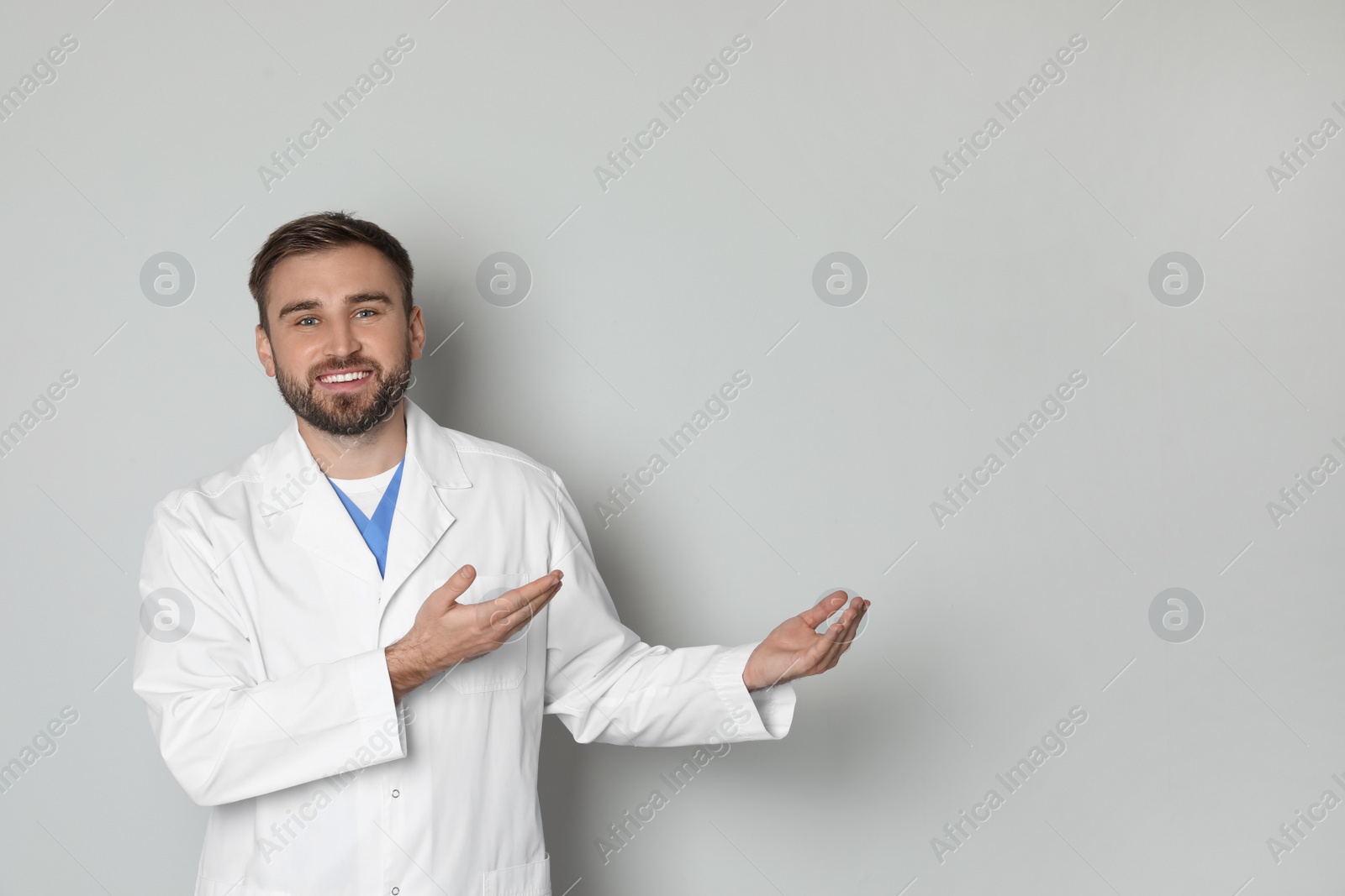 Photo of Portrait of young doctor on light grey background. Space for text