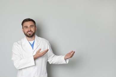 Portrait of young doctor on light grey background. Space for text