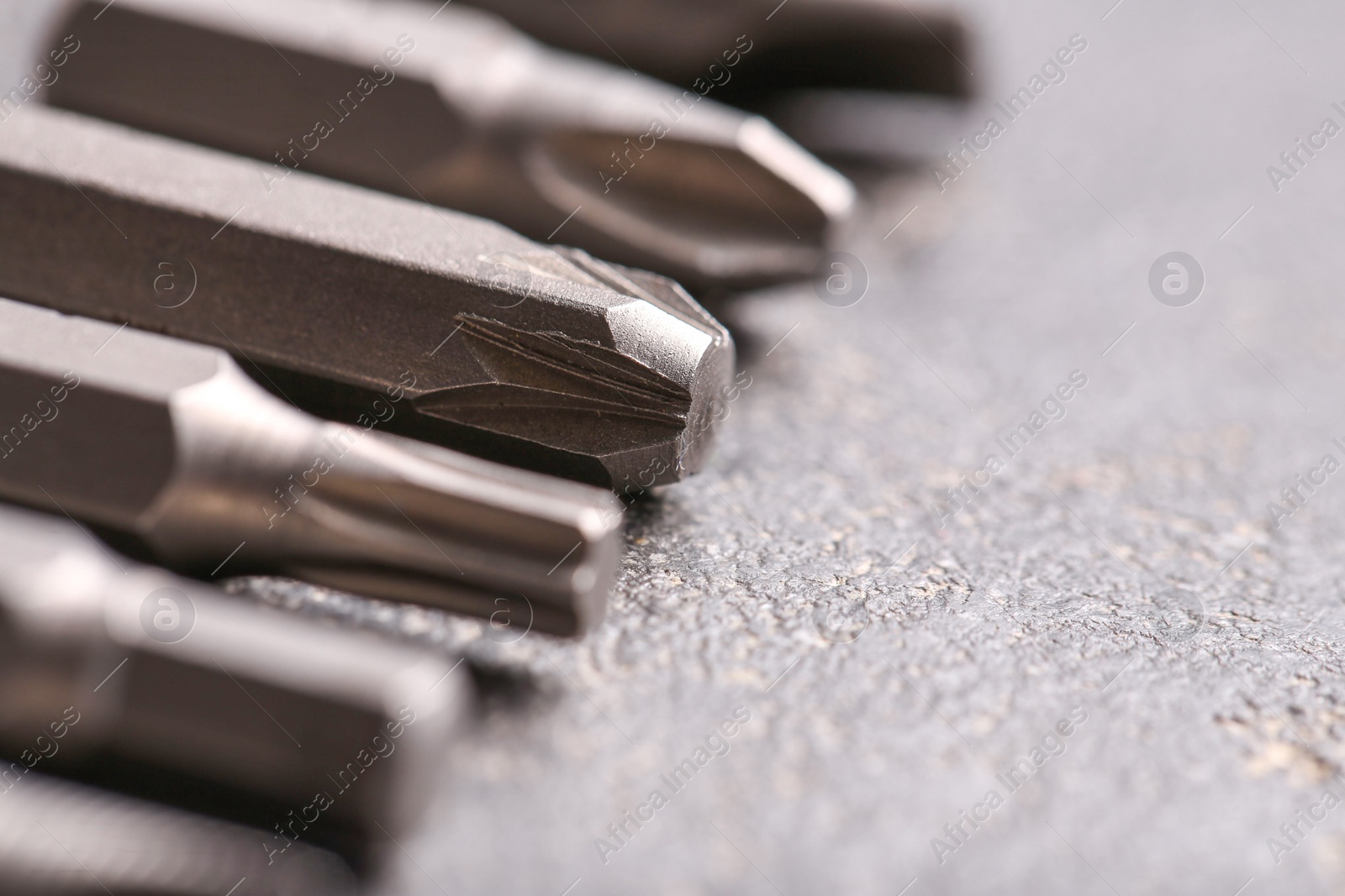 Photo of Different screwdriver bits on grey table, closeup