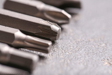 Different screwdriver bits on grey table, closeup