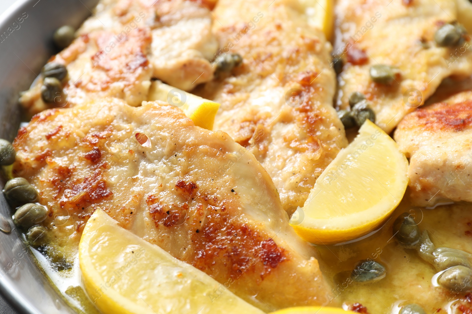 Photo of Delicious chicken piccata with lemons as background, closeup