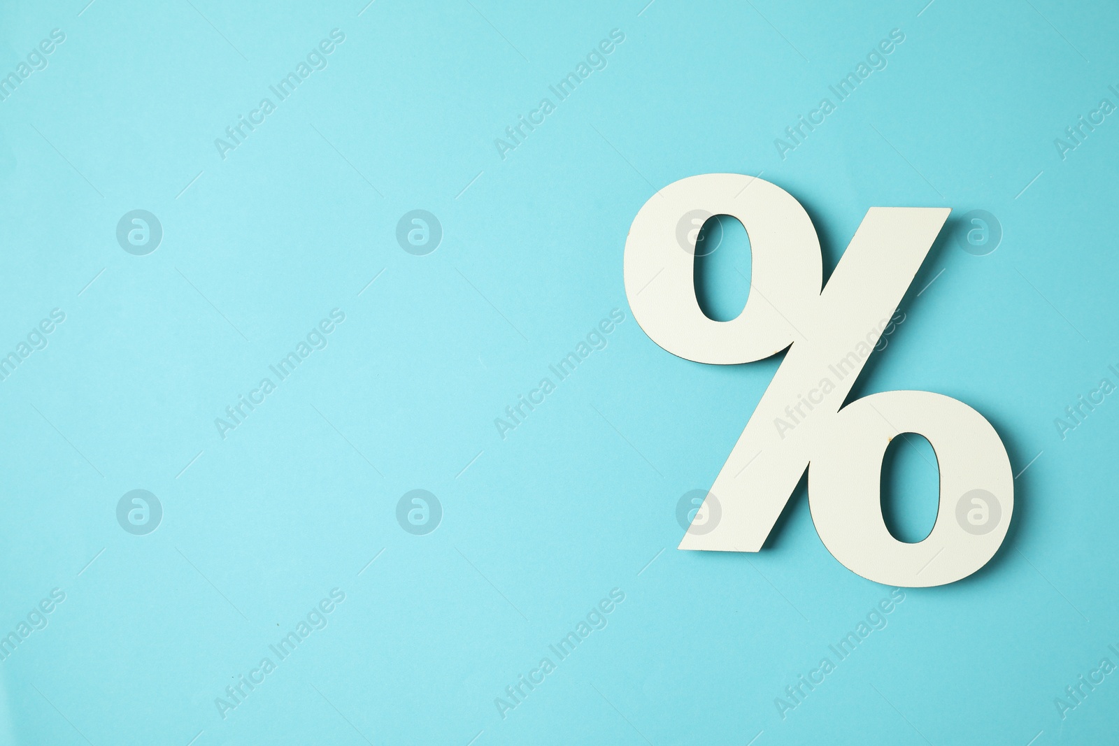 Photo of White percent sign on light blue background, top view. Space for text