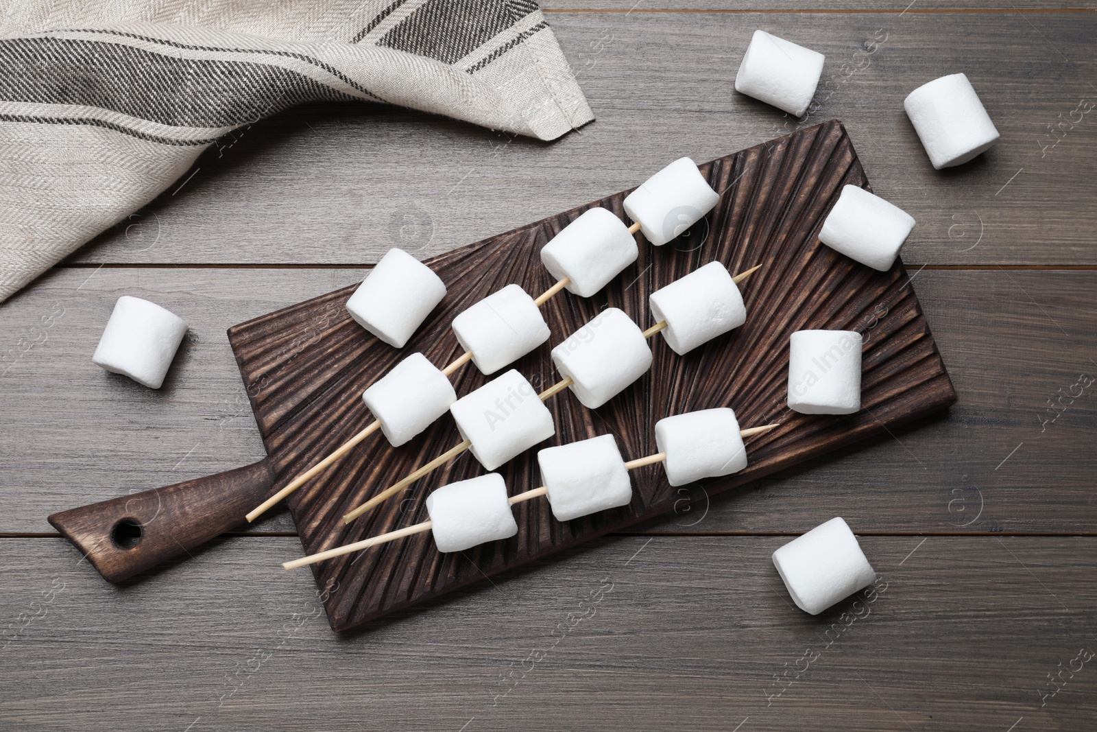 Photo of Sticks with marshmallows on wooden table, flat lay