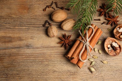 Photo of Different spices, nuts and fir branches on wooden table, flat lay. Space for text