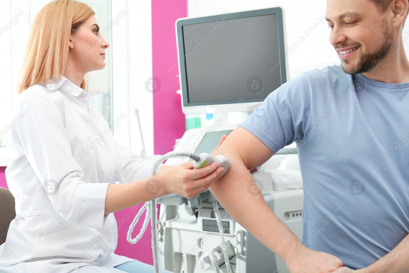 Photo of Doctor conducting ultrasound examination of elbow joint in clinic. Space for text