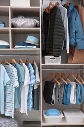 Photo of Stylish clothes and home stuff in large wardrobe closet