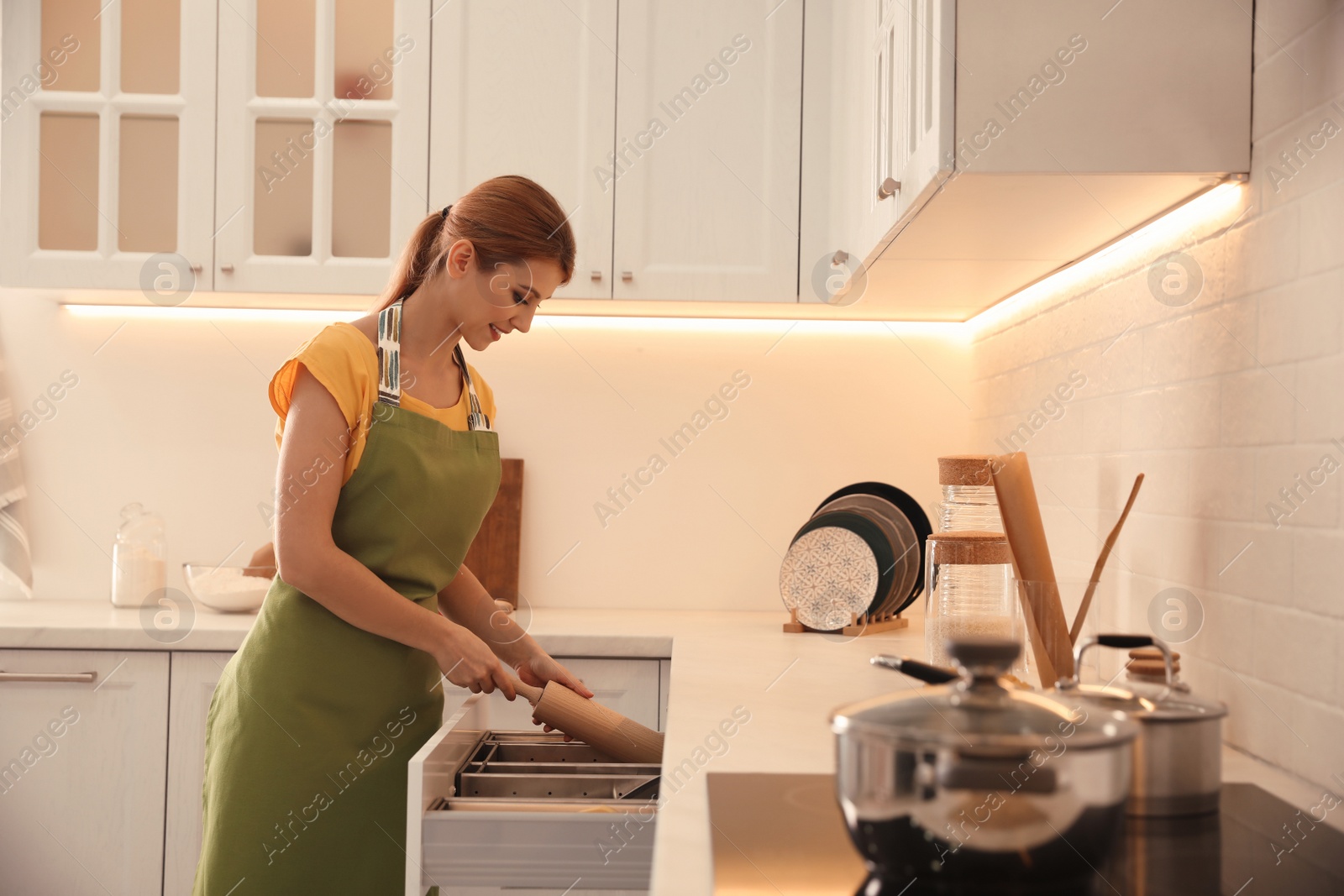 Photo of Beautiful young woman with rolling pin in kitchen