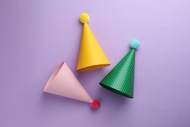 Photo of Beautiful party hats on purple background, top view