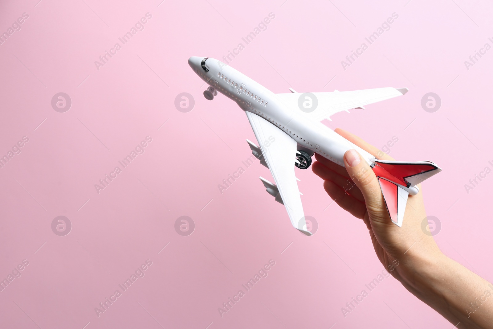 Photo of Woman holding toy airplane on pink background, closeup. Space for text