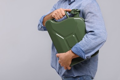 Photo of Man holding khaki metal canister on light grey background, closeup. Space for text