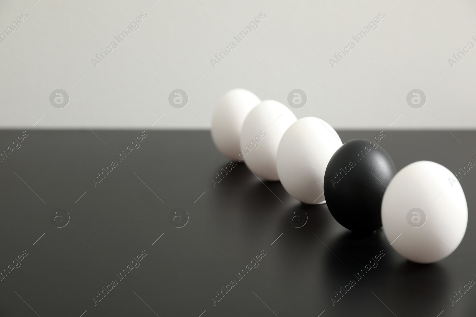Photo of Black egg among others on table. Space for text
