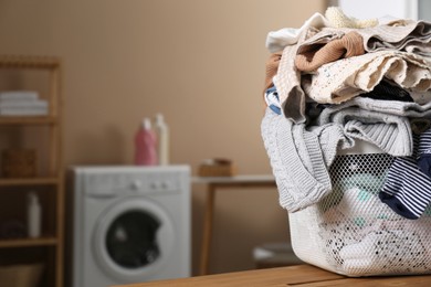 Photo of Laundry basket with baby clothes on wooden table in bathroom, space for text