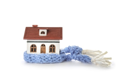 Photo of House model with knitted scarf on white background. Heating concept