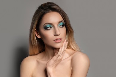 Photo of Young woman with evening makeup on grey background. Eye shadow product