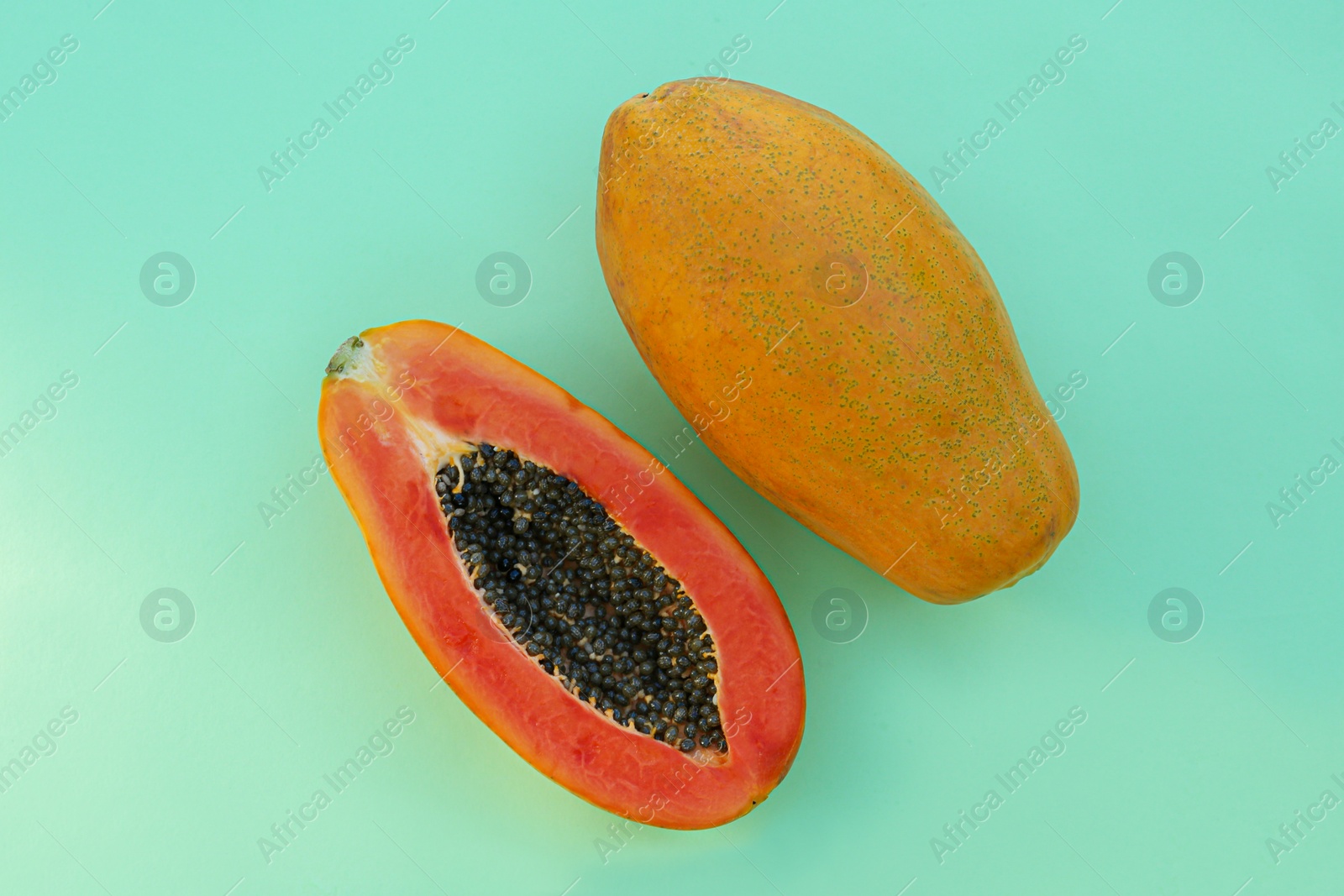 Photo of Fresh ripe papaya fruits on light turquoise background, flat lay