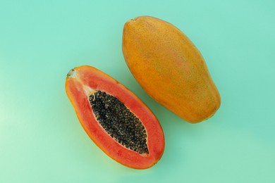 Fresh ripe papaya fruits on light turquoise background, flat lay