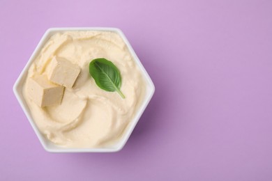 Photo of Delicious tofu sauce and basil leaf in bowl on violet background, top view. Space for text