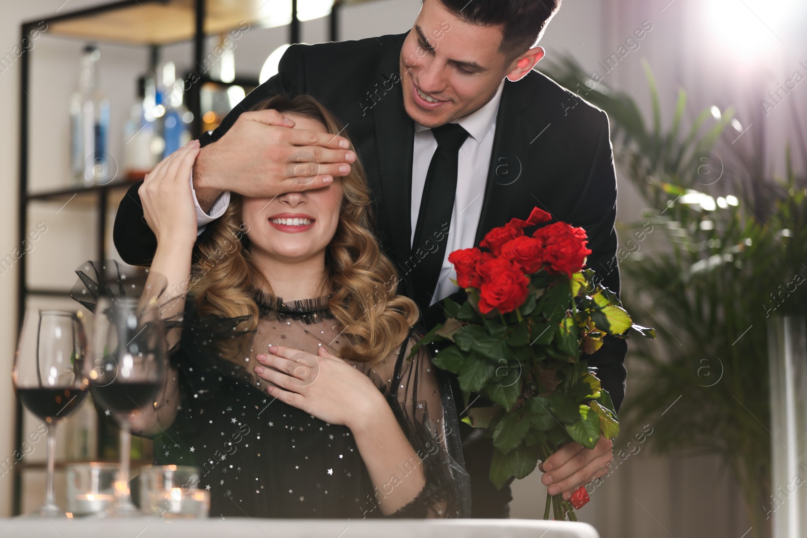 Photo of Man presenting roses to his beloved woman in restaurant at Valentine's day dinner