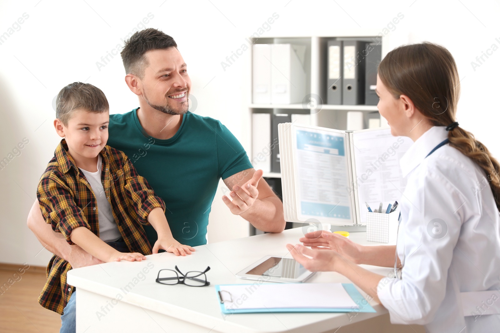 Photo of Father and son visiting pediatrician. Doctor working with little patient in hospital