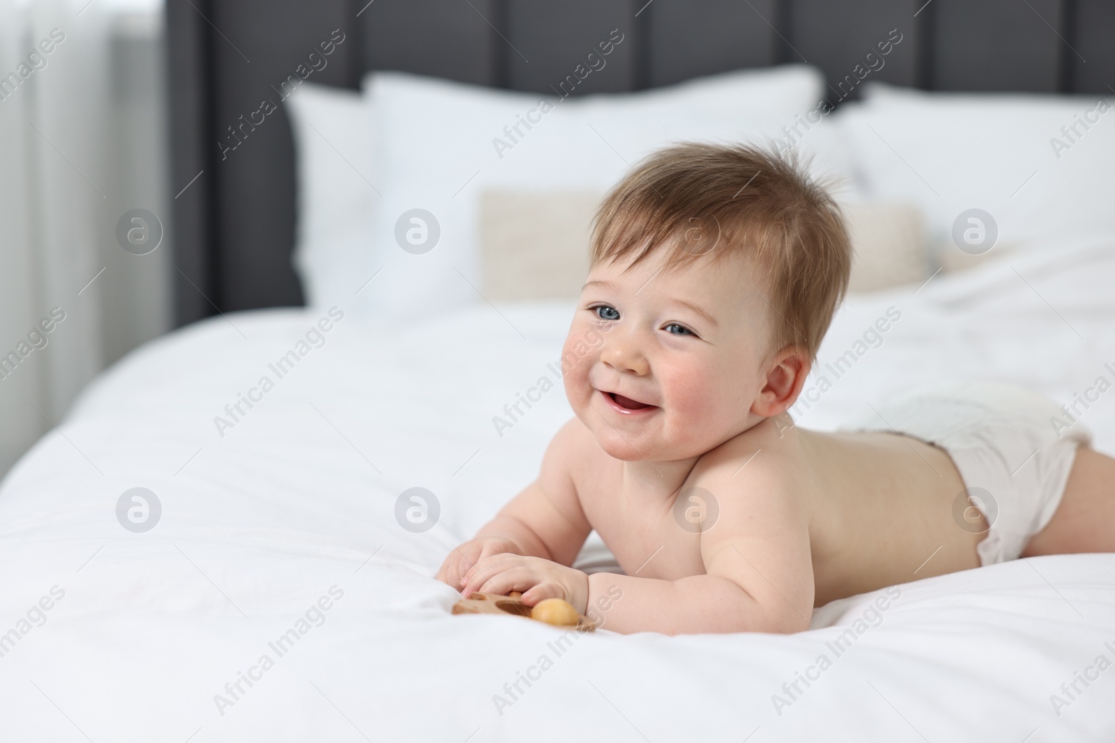 Photo of Cute baby boy with rattle lying on bed at home. Space for text
