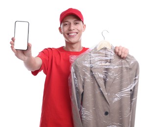 Dry-cleaning delivery. Happy courier holding jacket in plastic bag and smartphone on white background