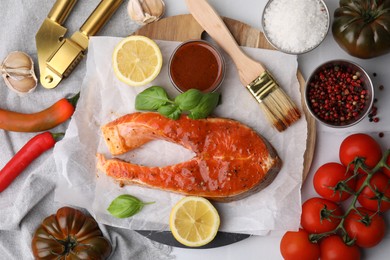 Photo of Fresh marinade, fish and other products on white tiled table, flat lay
