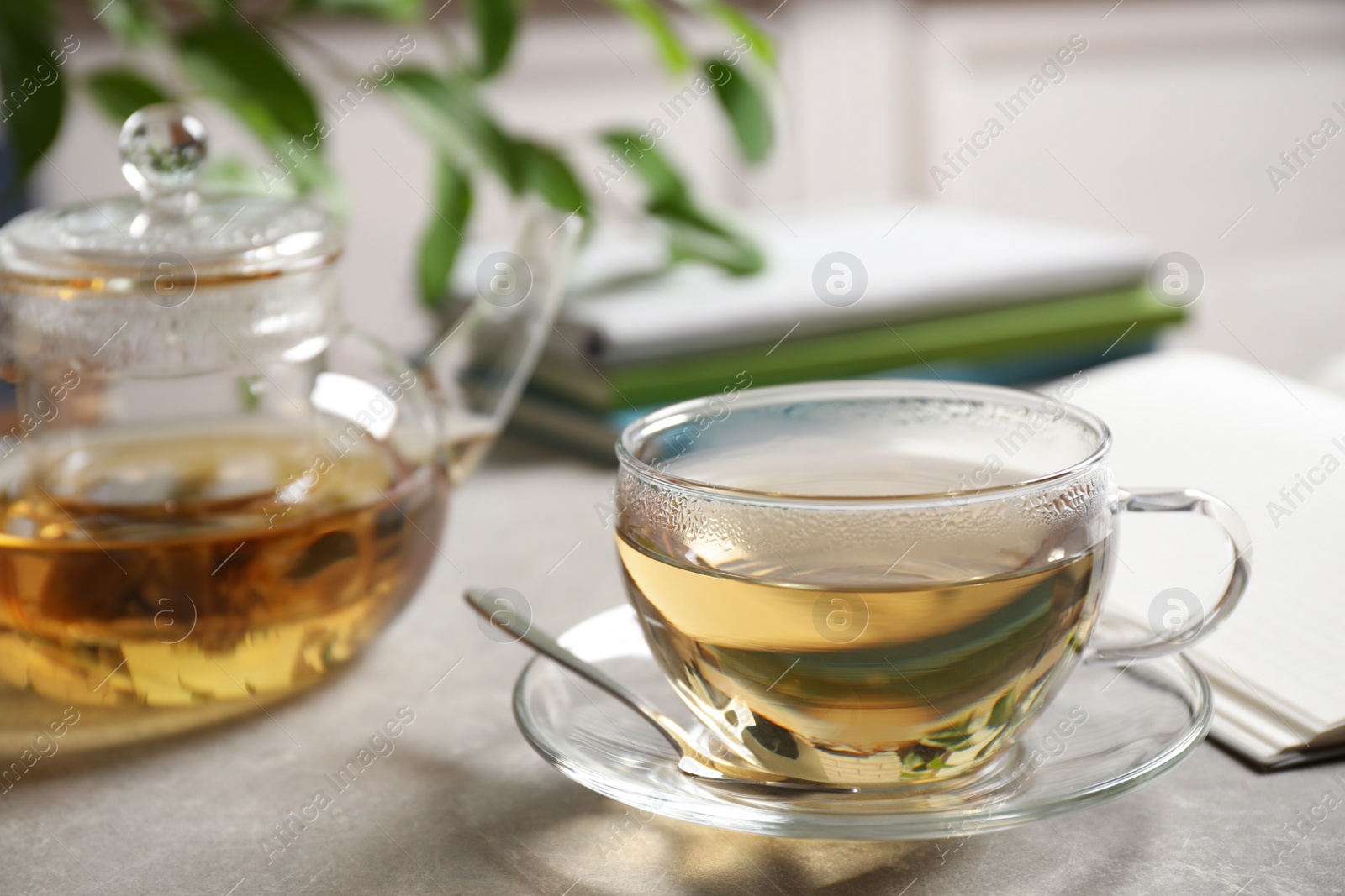 Photo of Tasty hot green tea in cup on grey table