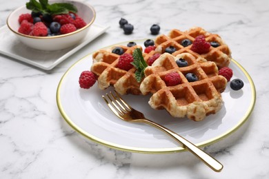 Photo of Delicious Belgian waffles with fresh berries and mint on white marble table, closeup