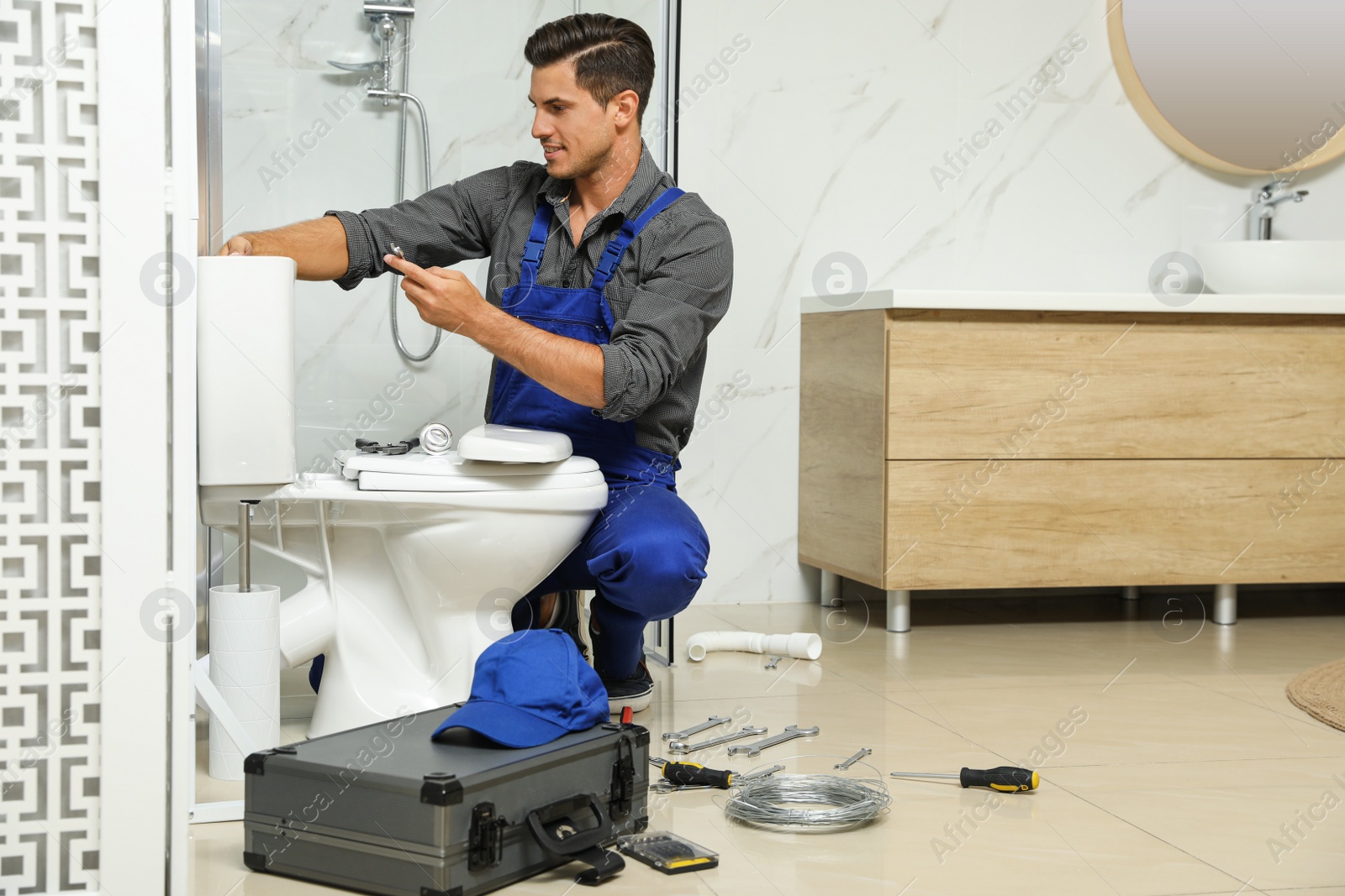 Photo of Professional plumber working with toilet bowl in bathroom