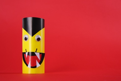 Photo of Funny yellow monster on red background, space for text. Halloween decoration