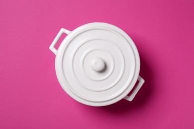 White pot with lid on dark pink background, top view