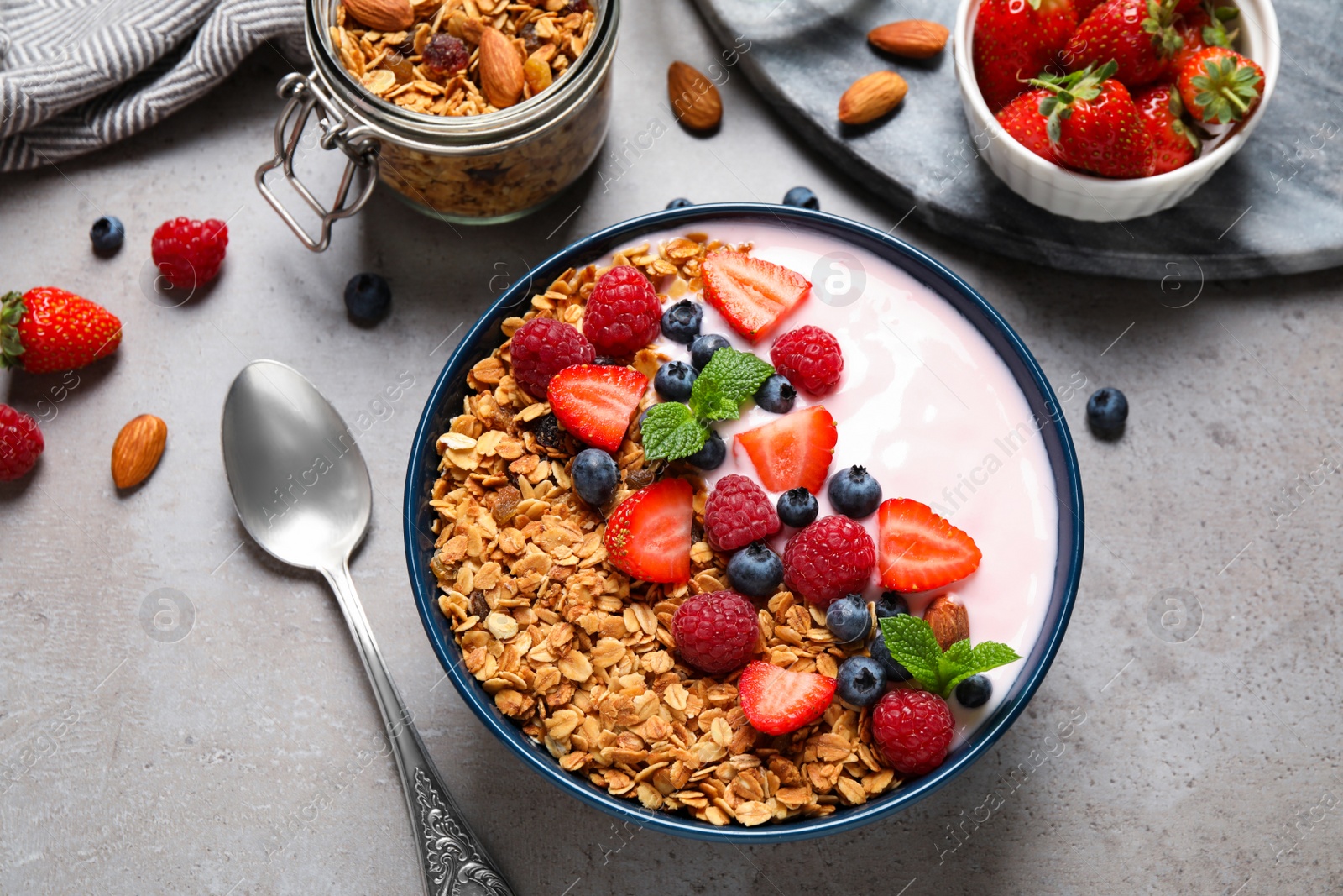 Photo of Tasty homemade granola with yogurt on grey table, flat lay. Healthy breakfast