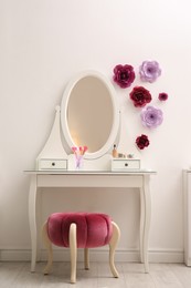 Stylish room interior with floral decor, dressing table and pouf