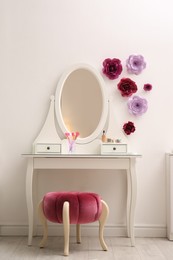 Photo of Stylish room interior with floral decor, dressing table and pouf