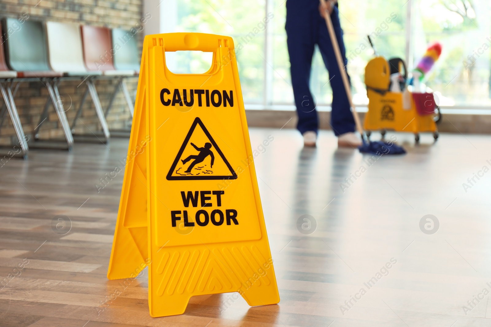 Photo of Safety sign with phrase Caution wet floor and blurred cleaner on background