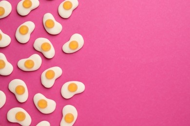 Photo of Tasty jelly candies in shape of egg on pink background, flat lay. Space for text