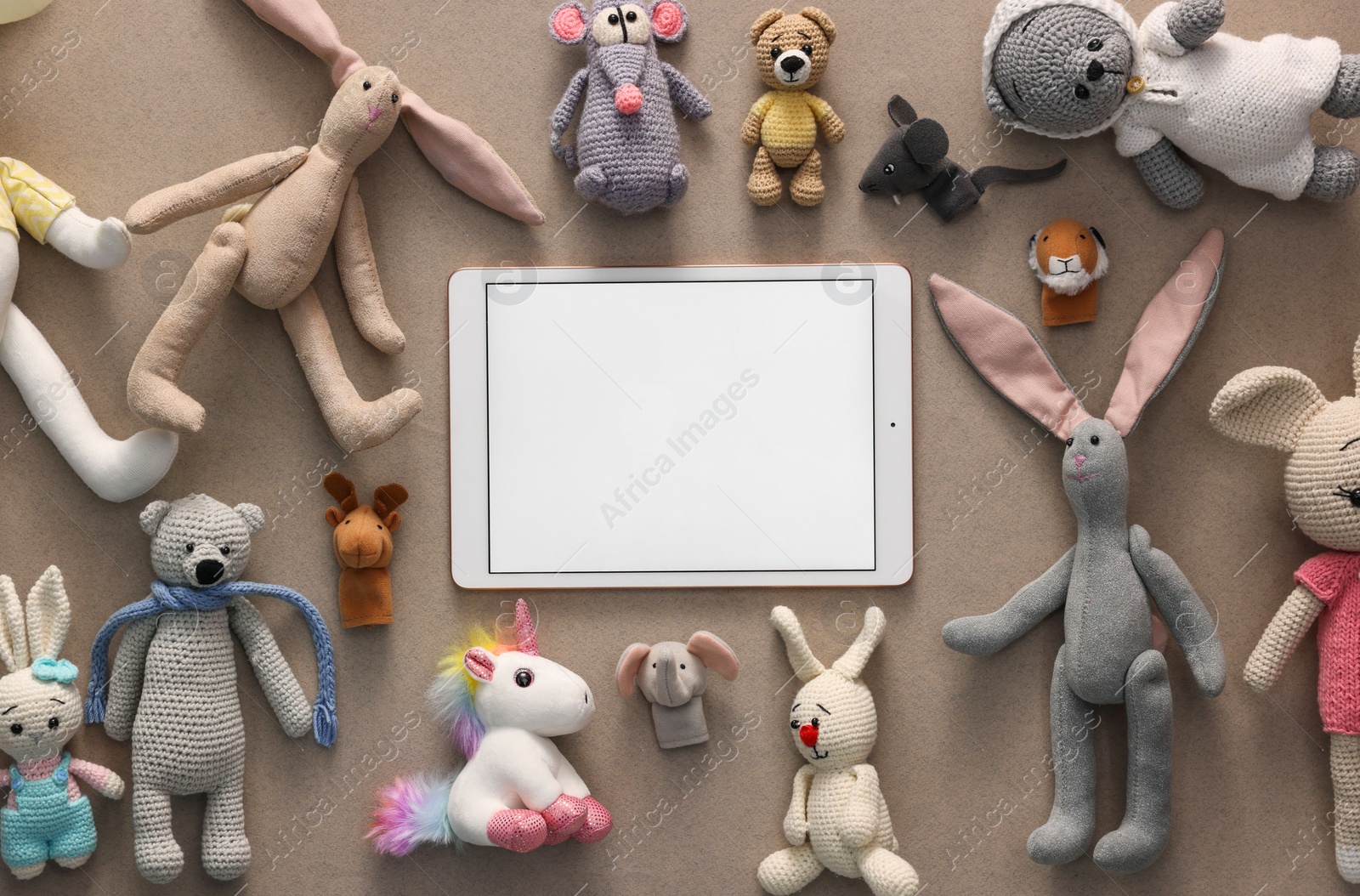 Photo of Modern tablet and kid's toys on light brown background, flat lay. Space for text