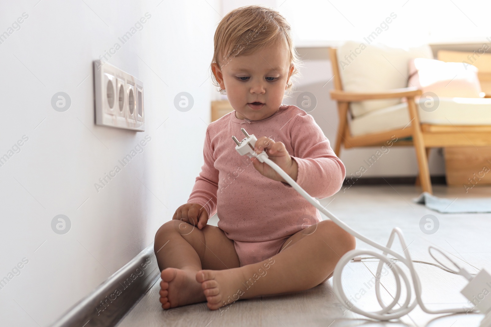 Photo of Cute baby playing with plug at home. Dangerous situation