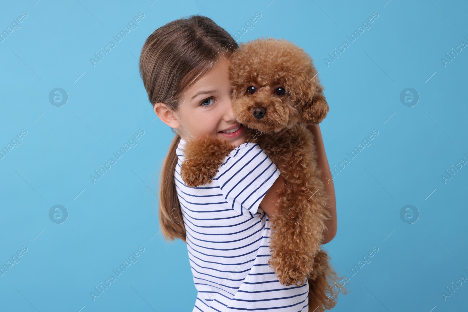 Photo of Little child with cute puppy on light blue background. Lovely pet