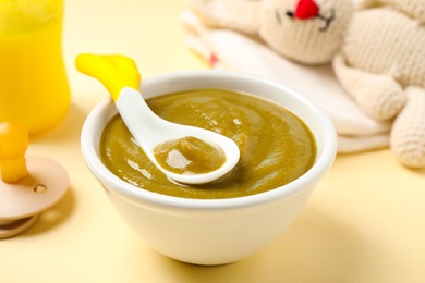 Photo of Bowl of healthy baby food on yellow background, closeup