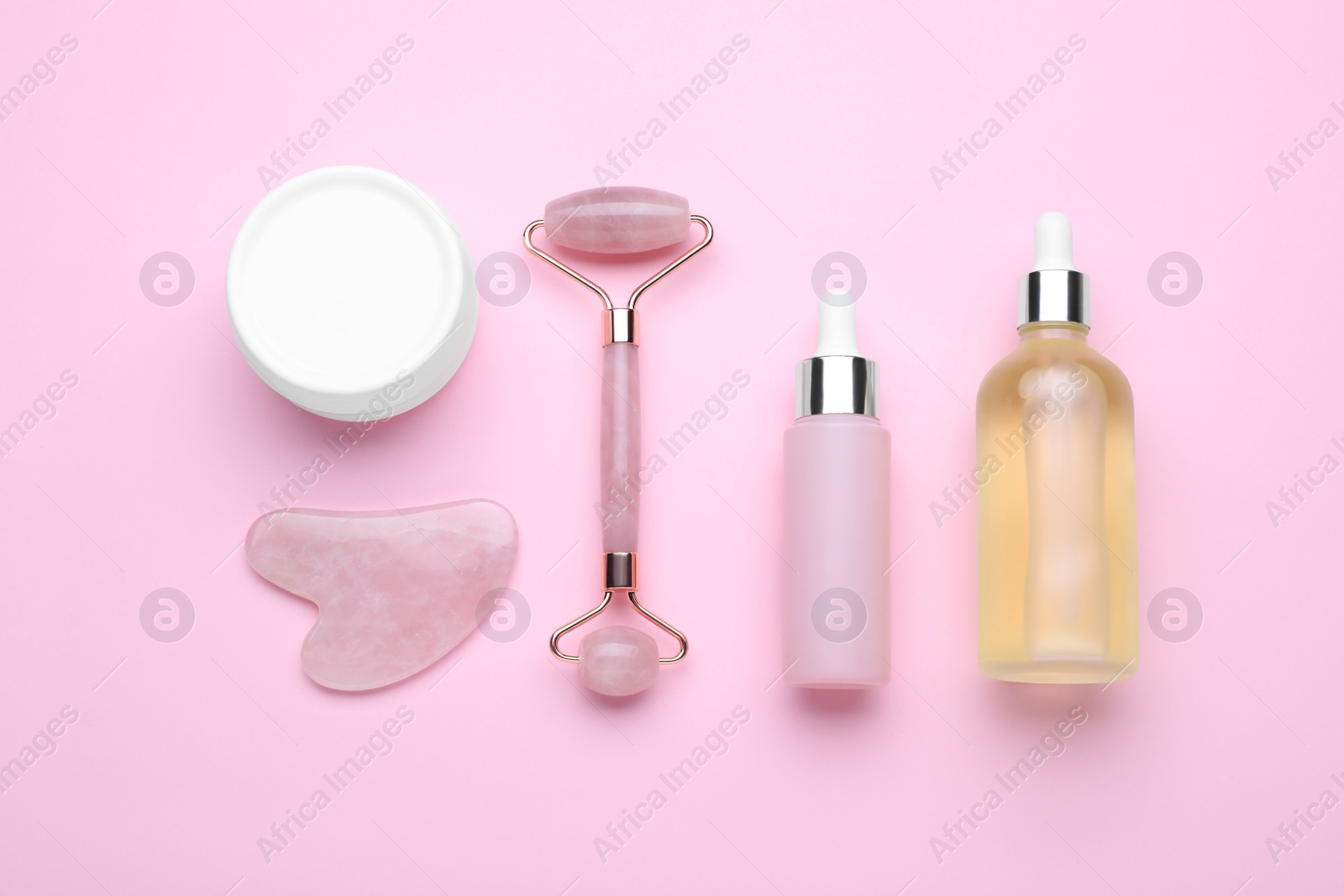 Photo of Natural face roller, gua sha tool and cosmetic products on pink background, flat lay