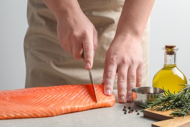 Photo of Man cutting raw salmon at grey table, closeup