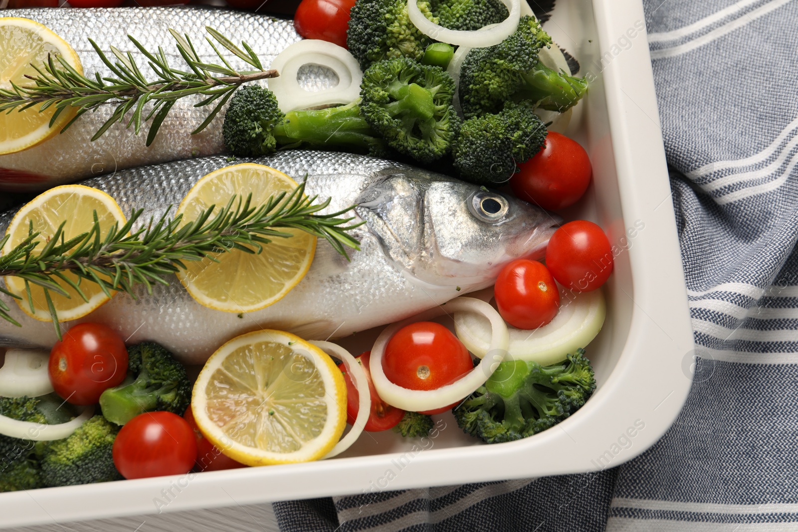 Photo of Raw fish with vegetables and lemon in baking dish on table, top view